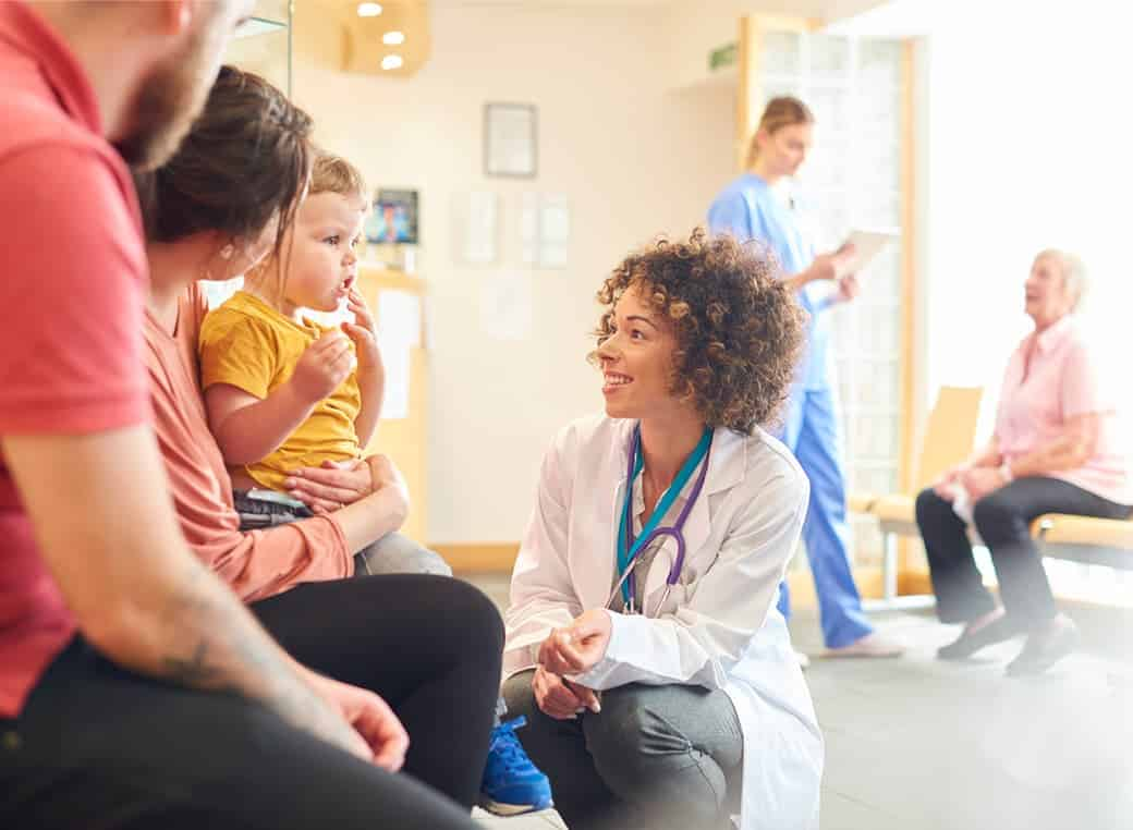 Doctor talks with mother and child in clinic waiting room