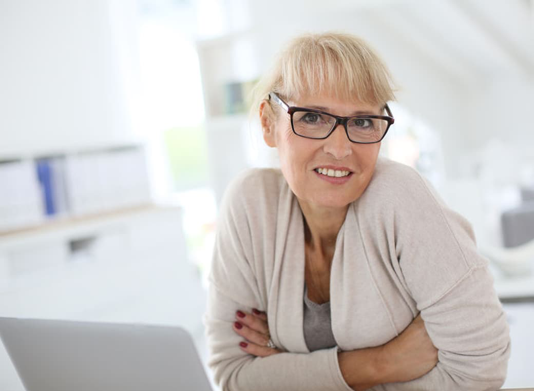 A senior woman sitting at a laptop computer.