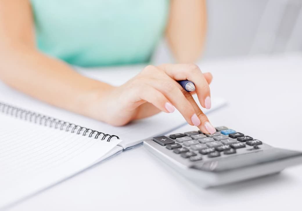 A woman using a calculator at a desk.
