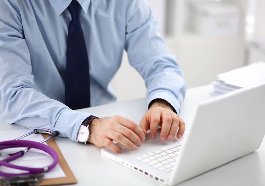 Medical provider typing on a laptop.