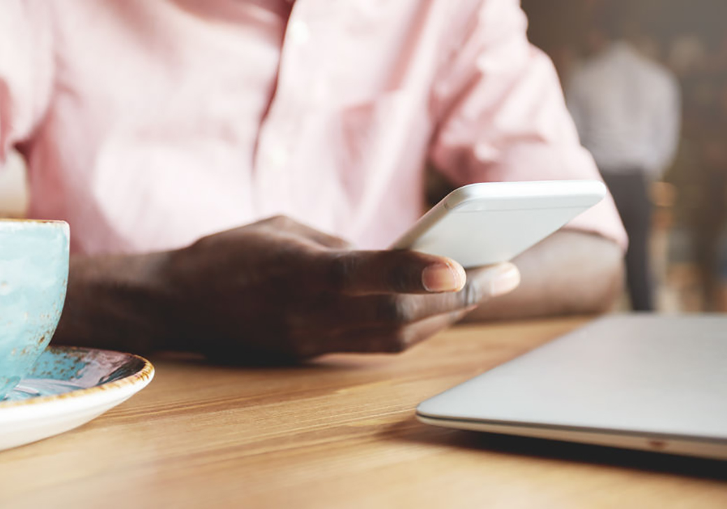Man sitting in a coffee shop holding mobile phone.