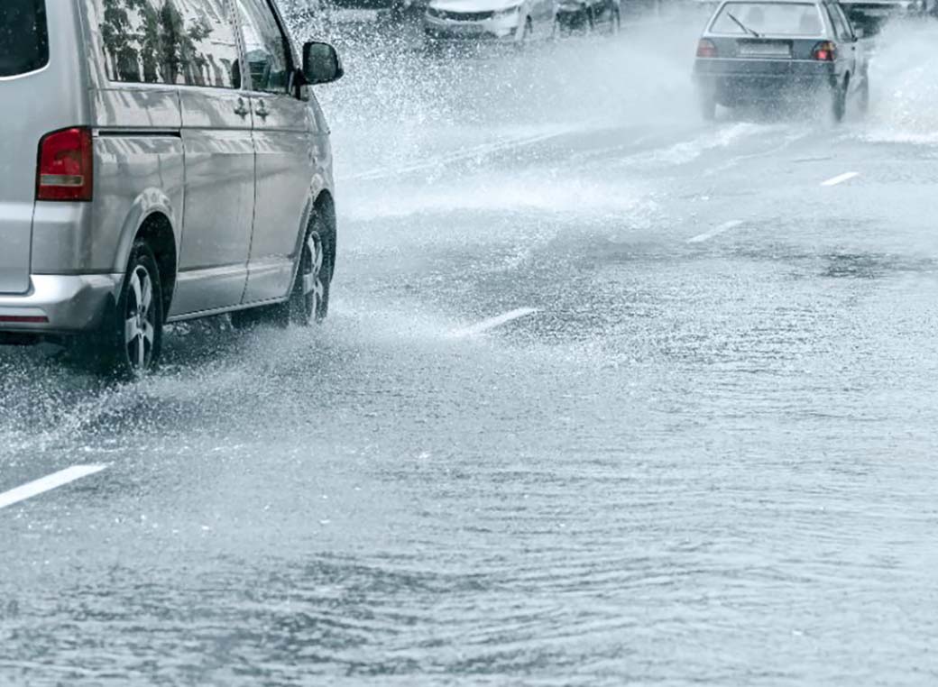 Cars driving through flooded city road after heavy rain.