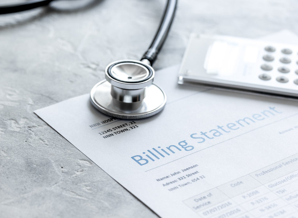 Stethoscope on gray stone background next to an insurance billing statement. 