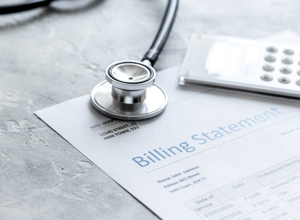 Stethoscope on gray stone background next to an insurance billing statement.