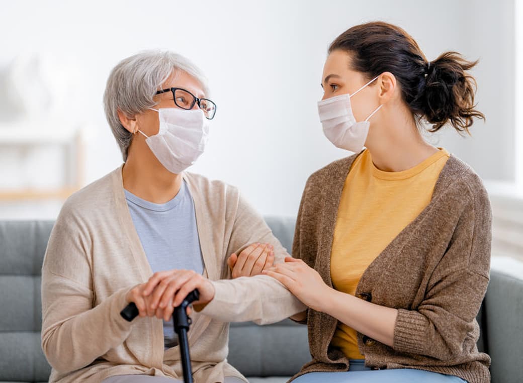 Adult daughter and senior parent wearing face masks.