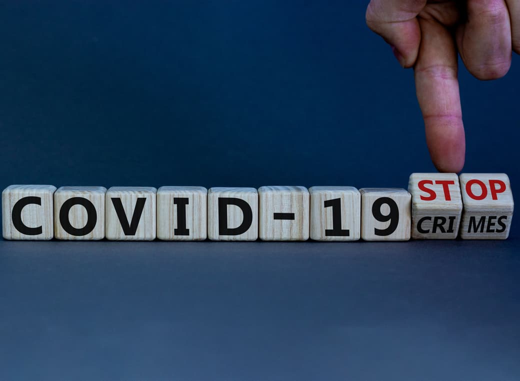 Hand turns cubes with the words stop COVID-19 crimes.