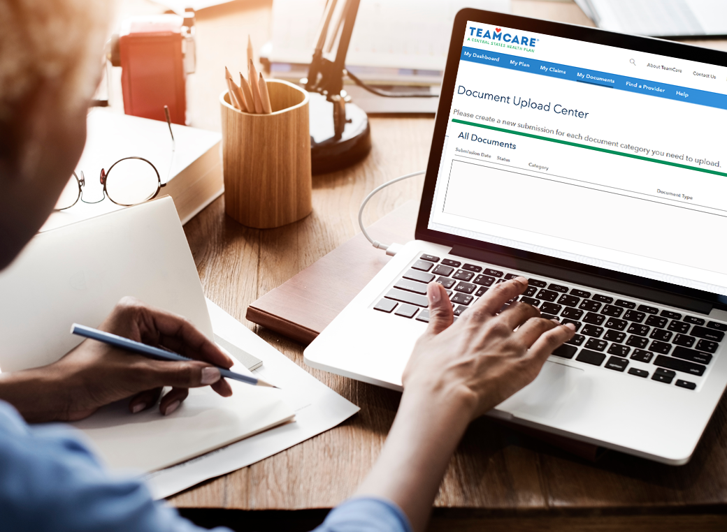 An aerial view of a woman on her computer and the screen is showing the Document Upload Center feature.