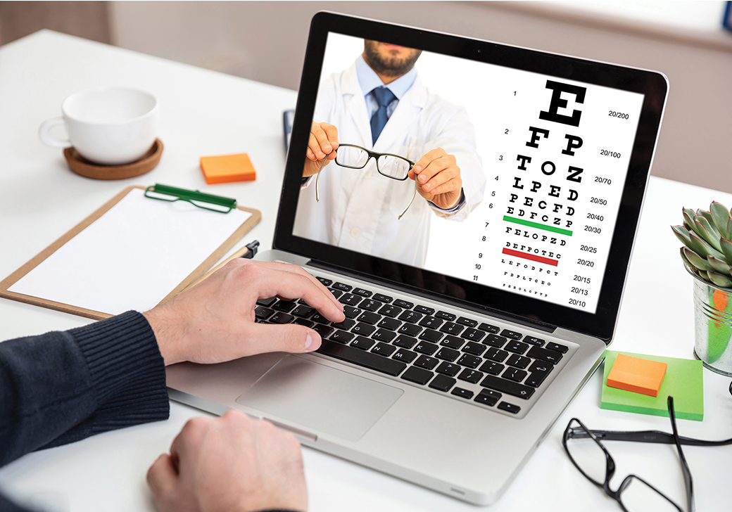 A person on a laptop with an image of an eye exam on the screen. 