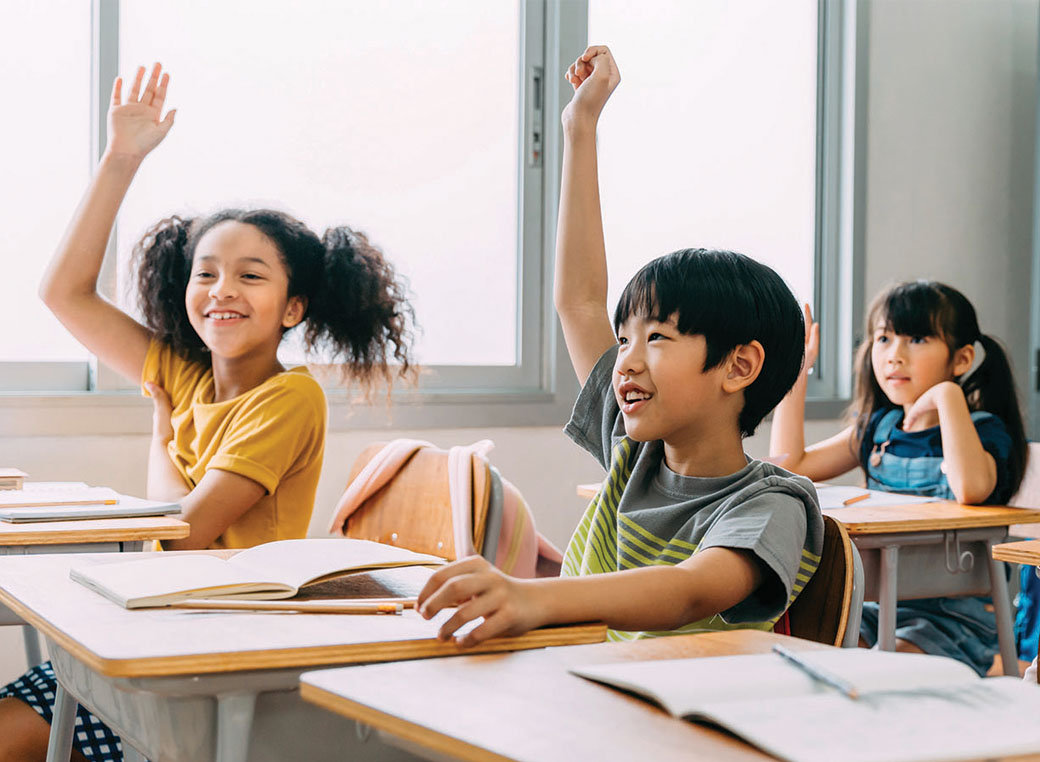 Students in classroom raising their hands