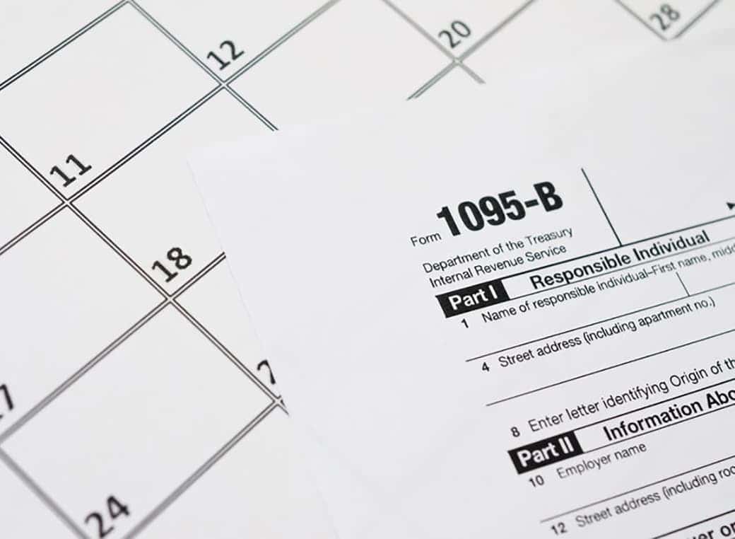 IRS Form 1095-B  blank tax form lies on empty calendar page