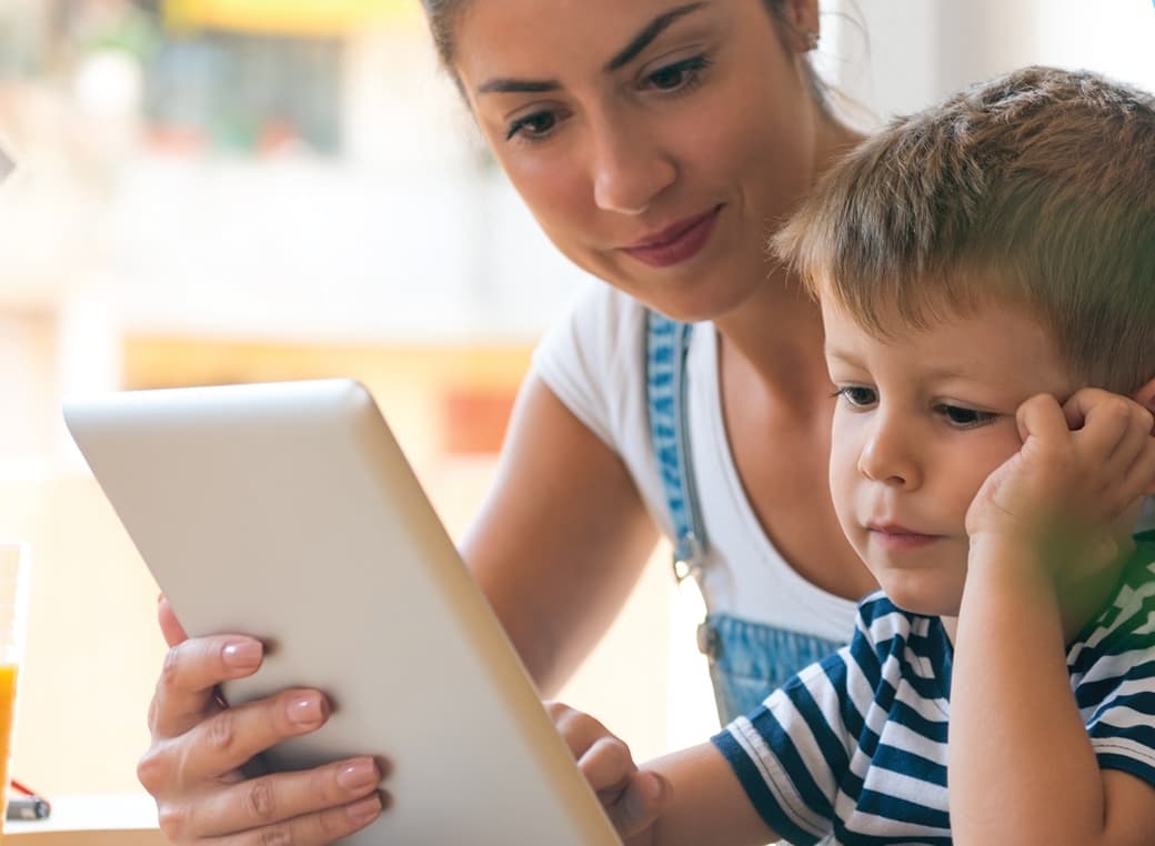 Mother and son on a Teladoc call on a tablet device.