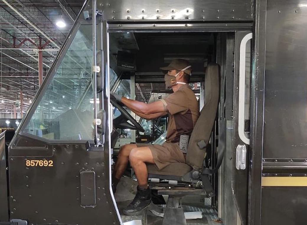 UPS driver in delivery truck wearing a face mask.
